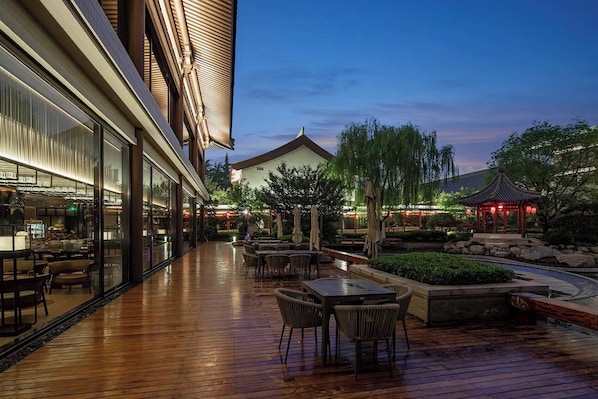 Un espace extérieur aménagé en terrasse, avec un revêtement de sol en bois, des coins salon et un gazebo de style traditionnel.