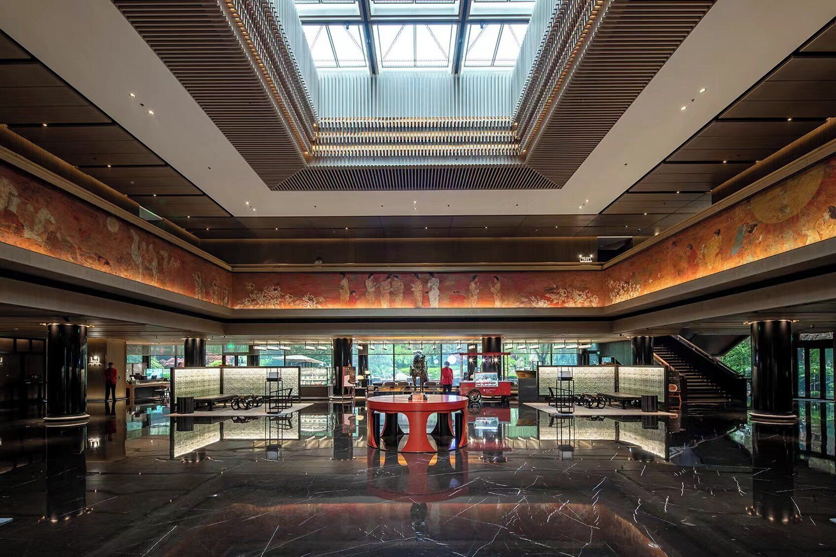 A spacious lobby with a high ceiling, a central seating area, and a large window providing natural light.