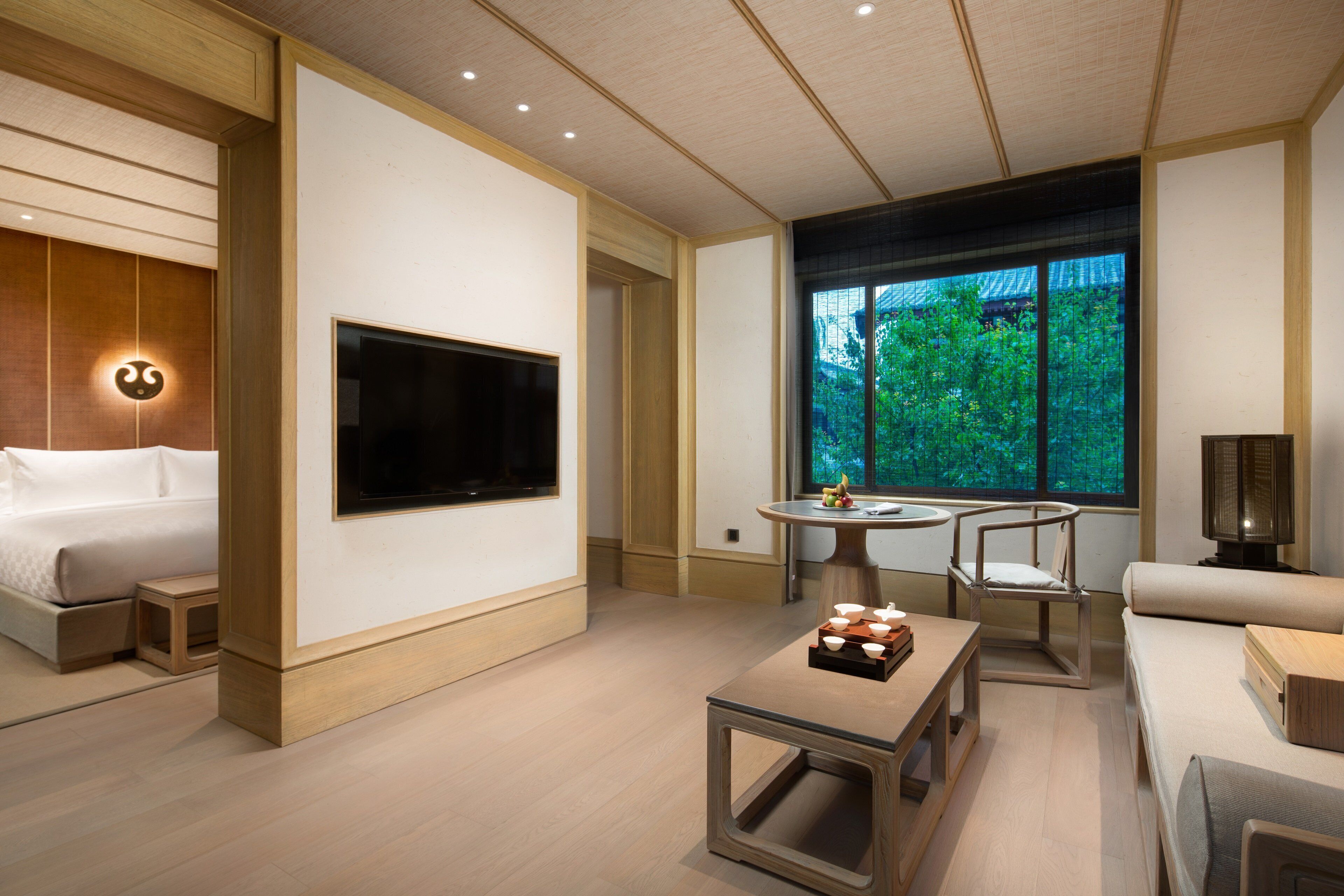 Una habitación de hotel moderna con una cama, un televisor, una mesa de comedor y un sofá.