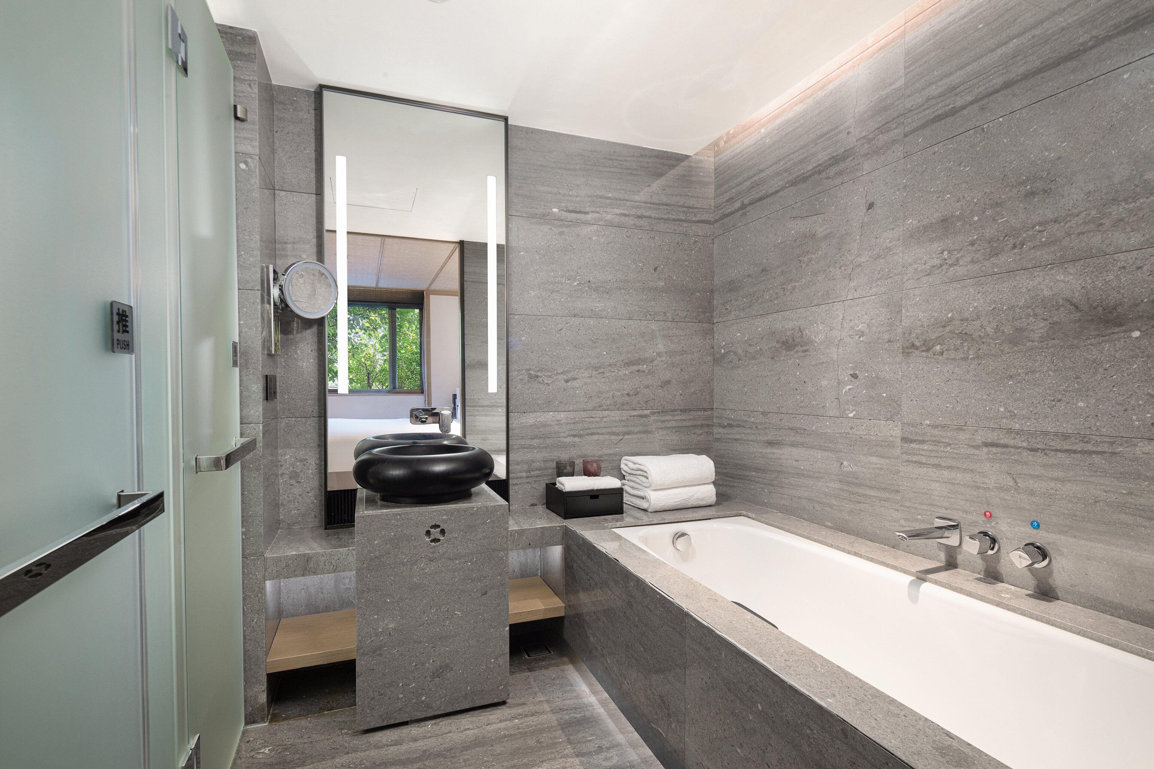 Un baño moderno con una bañera grande, un espejo redondo y un lavabo.