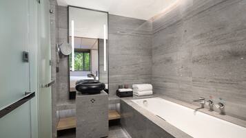 Un baño moderno con una bañera grande, un espejo redondo y un lavabo.
