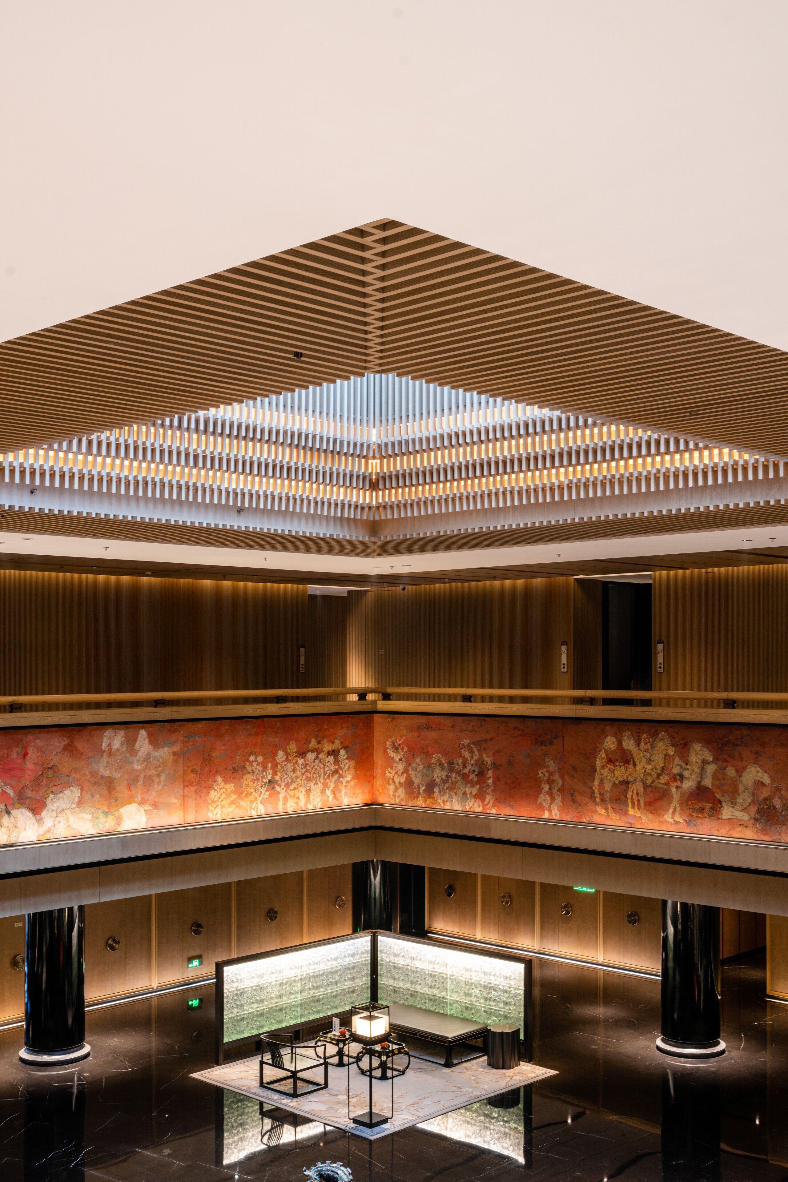 A spacious lobby with a high ceiling, a central seating area, and a decorative wall.