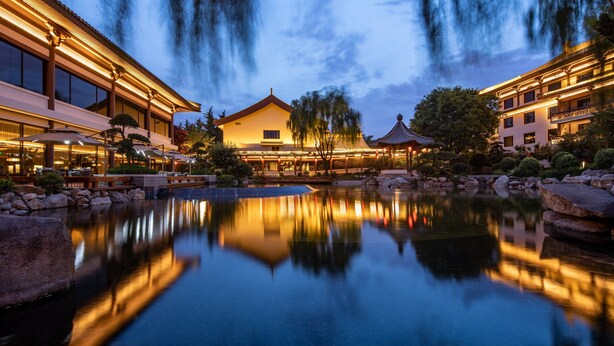 A hotel with a reflection pool, traditional architecture, and a well-lit outdoor area. - HUALUXE Hotels and Resorts Xi'an Tanghua, an IHG hotel (Xi'an)