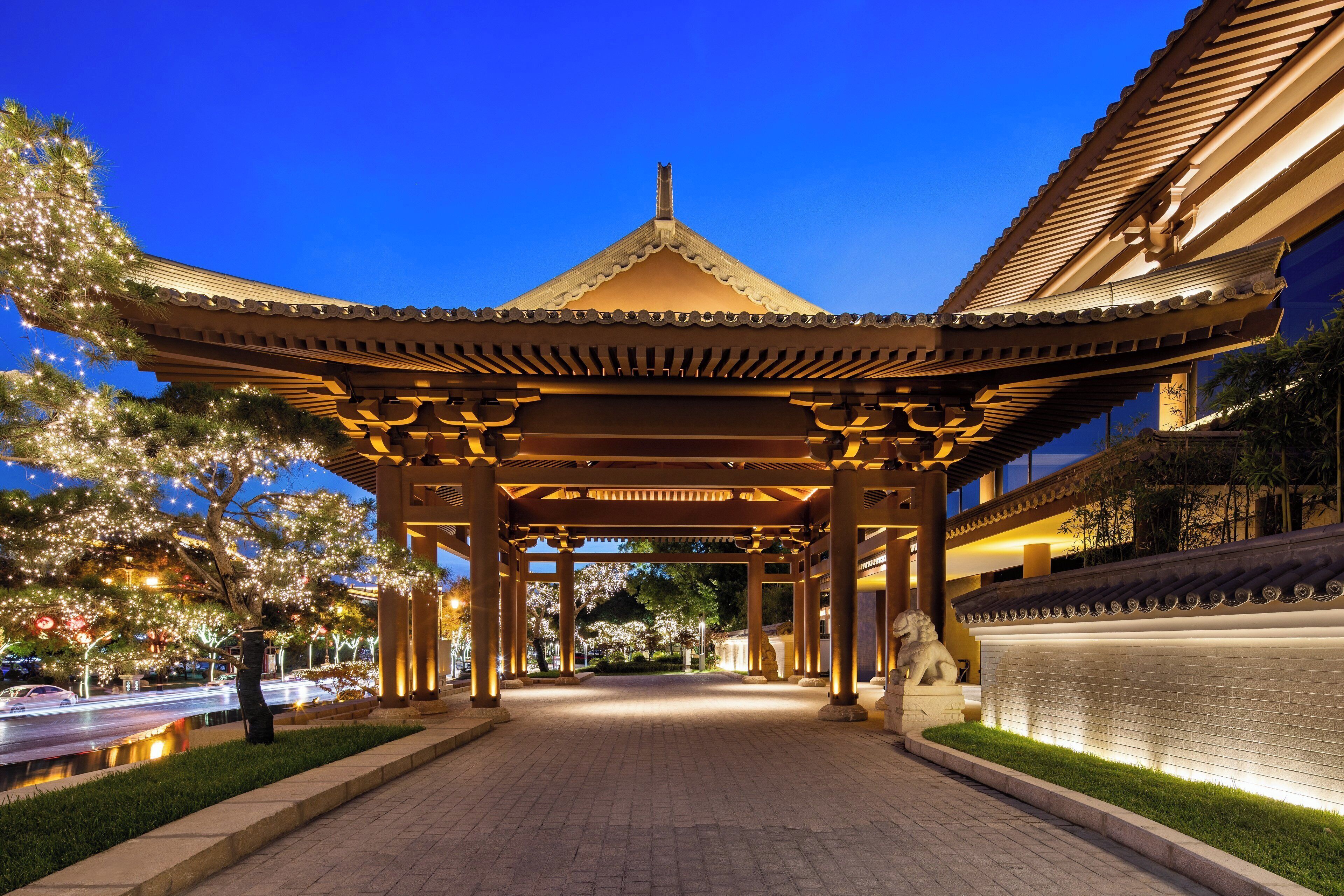 A traditional pavilion with a tiled roof, surrounded by well-maintained greenery and a paved walkway.