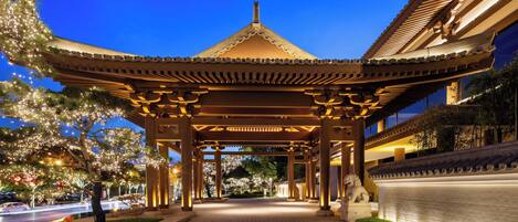 A traditional pavilion with a tiled roof, surrounded by well-maintained greenery and a paved walkway.