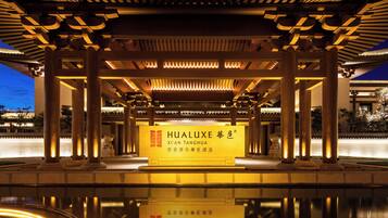A traditional pavilion with illuminated pillars and a reflective pool in front.