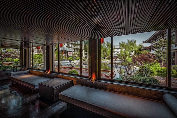 A modern interior with large windows, seating areas, and a view of a traditional courtyard. - HUALUXE Hotels and Resorts Xi'an Tanghua, an IHG hotel (Xi'an)