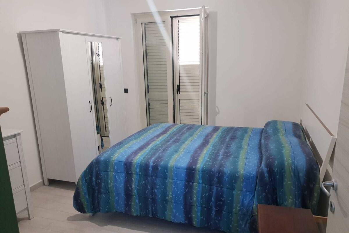 A bedroom with a bed, a wardrobe, and a door.