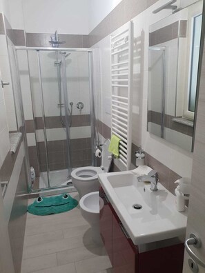A modern bathroom with a glass-enclosed shower, a toilet, a sink, and a mirror. - Casa Vacanze Mercolino (Bracigliano)