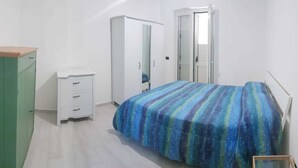 Un dormitorio con cama, armario, cómoda y puerta.