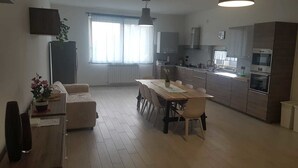 Una cocina moderna con comedor, un ventanal grande y una lámpara colgante.