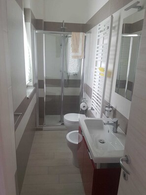 Tweepersoonskamer, privébadkamer | Badkamer | Een douche, een bidet, handdoeken, zeep