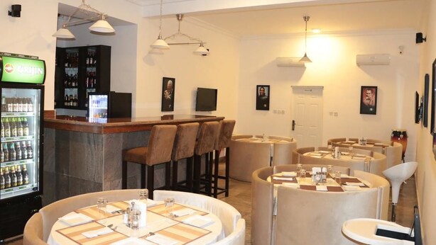 Un restaurant avec des tables rondes, un bar et un réfrigérateur rempli de boissons.