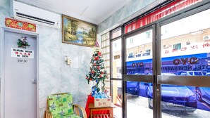 Un espace d’accueil d’hôtel décoré d’un sapin de Noël, d’un fauteuil en osier et d’un panneau indiquant que l’accès est réservé au PERSONNEL.