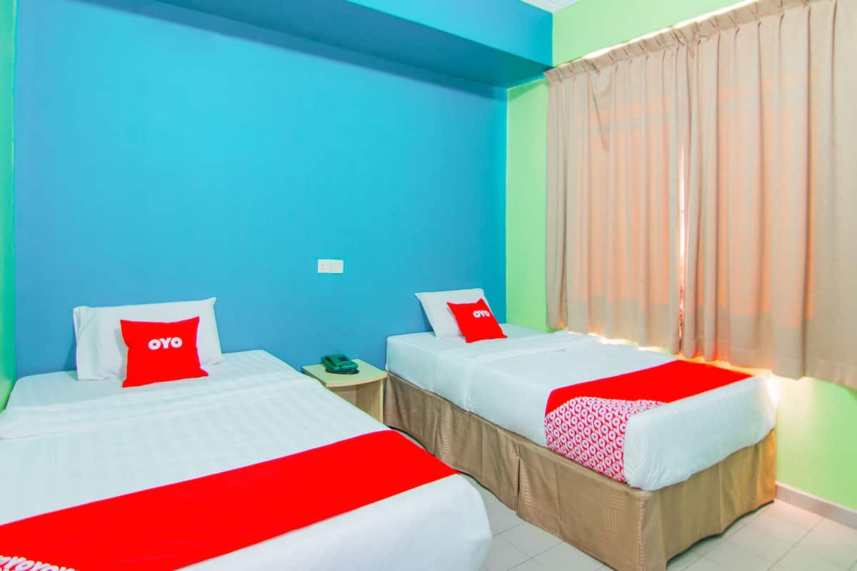 Een hotelkamer met twee bedden, elk voorzien van een rode en witte dekbedovertrek, en een groene muur.