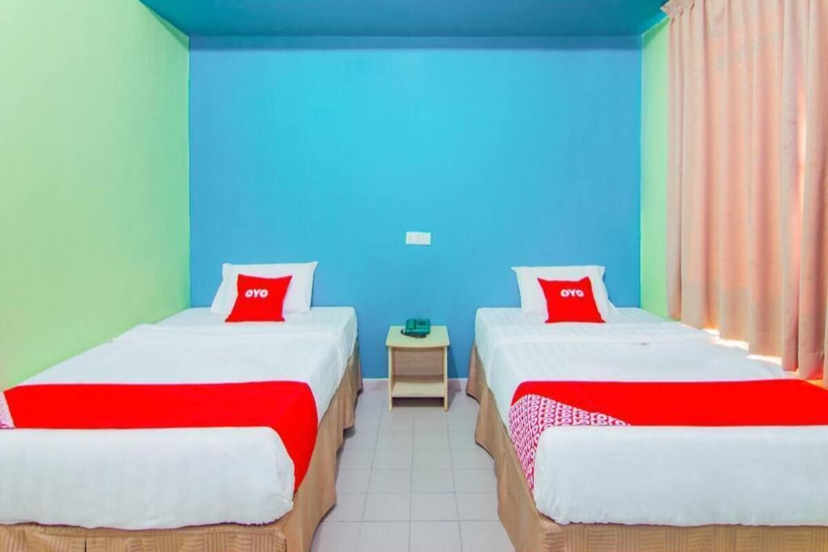 Een kamer met twee bedden, elk met een rood kussen, een klein tafeltje en een blauwe wand.