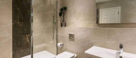 Un baño moderno con ducha acristalada, inodoro y lavamanos.