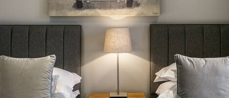 A hotel room with two beds, a nightstand with a lamp, and a painting on the wall.