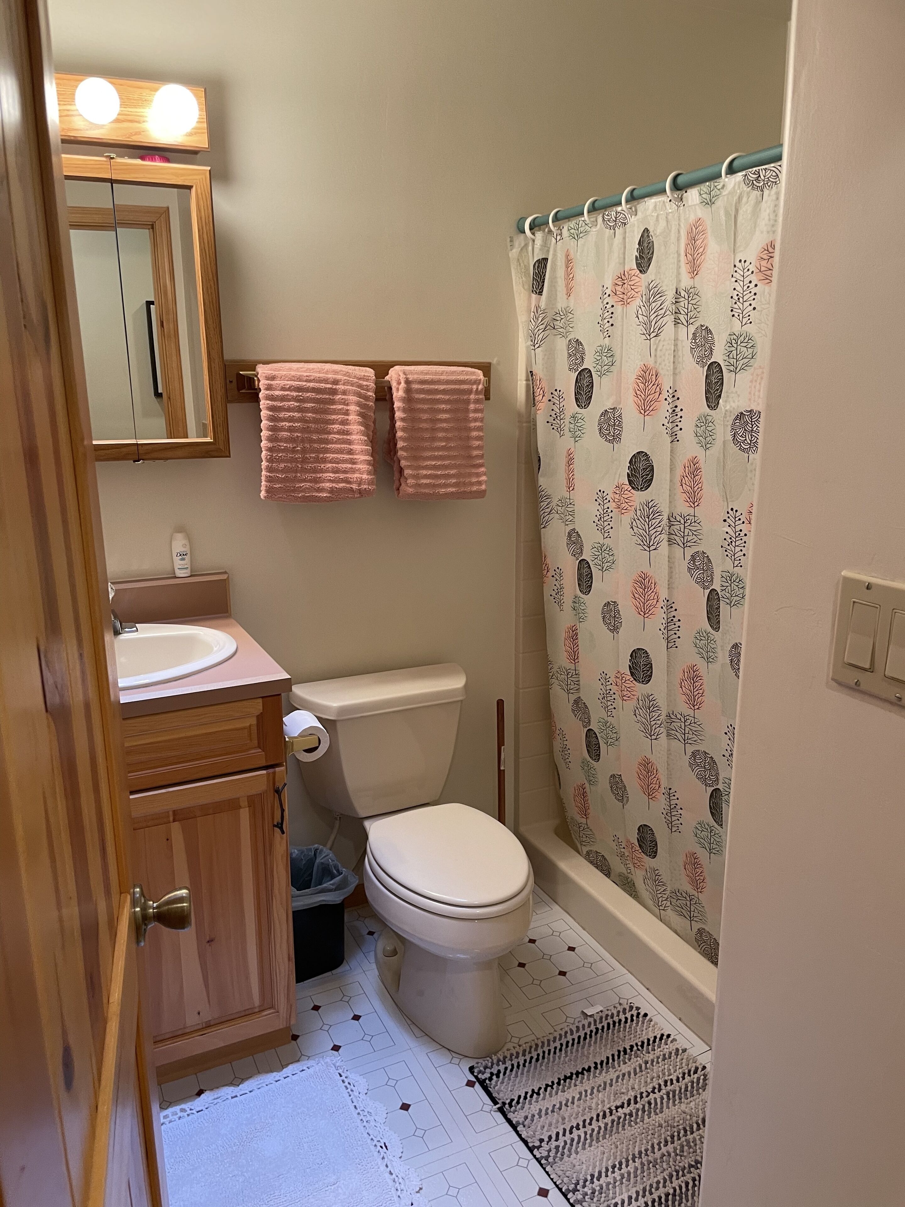 Un baño con inodoro, lavabo, espejo y cortina de ducha.