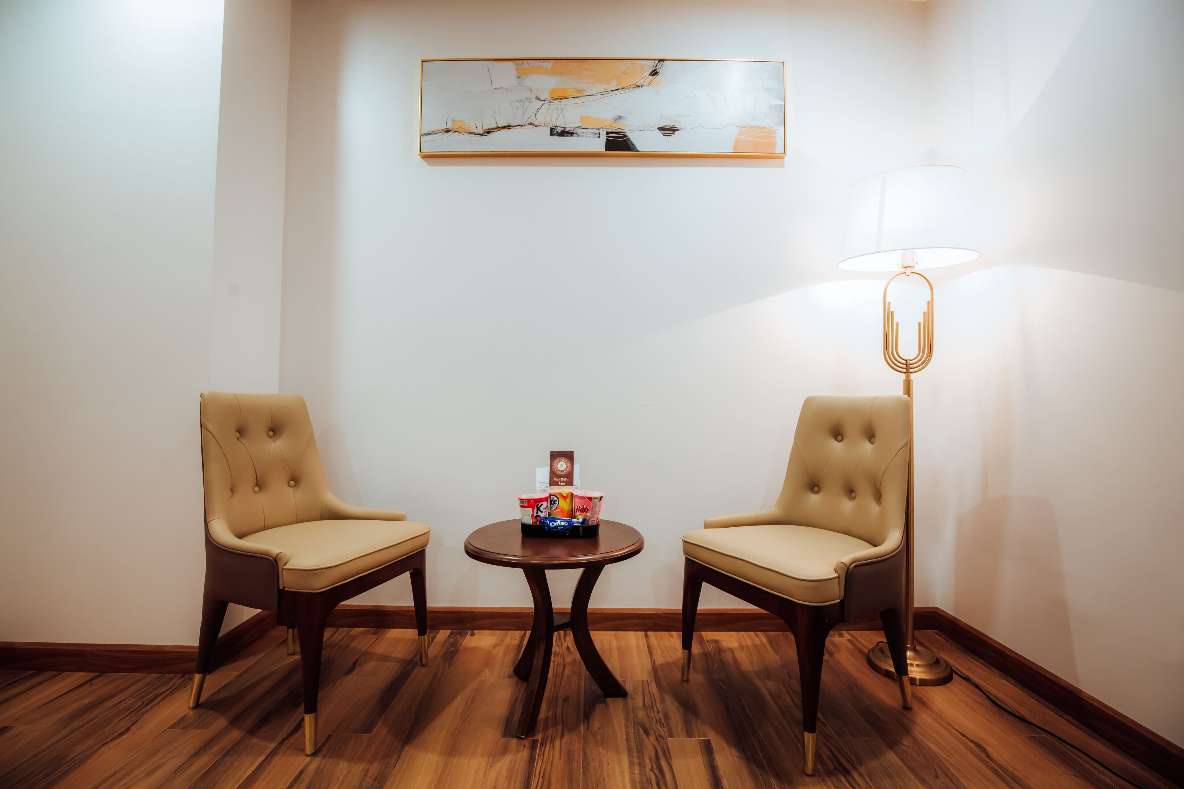 A room with two leather chairs, a small table with a coffee machine, and a lamp.
