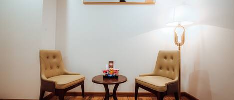 A room with two leather chairs, a small table with a coffee machine, and a lamp.