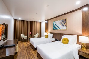 A hotel room with two beds, a desk, a chair, a TV, and a painting on the wall. - Menrva Hotel (Hai Phong)