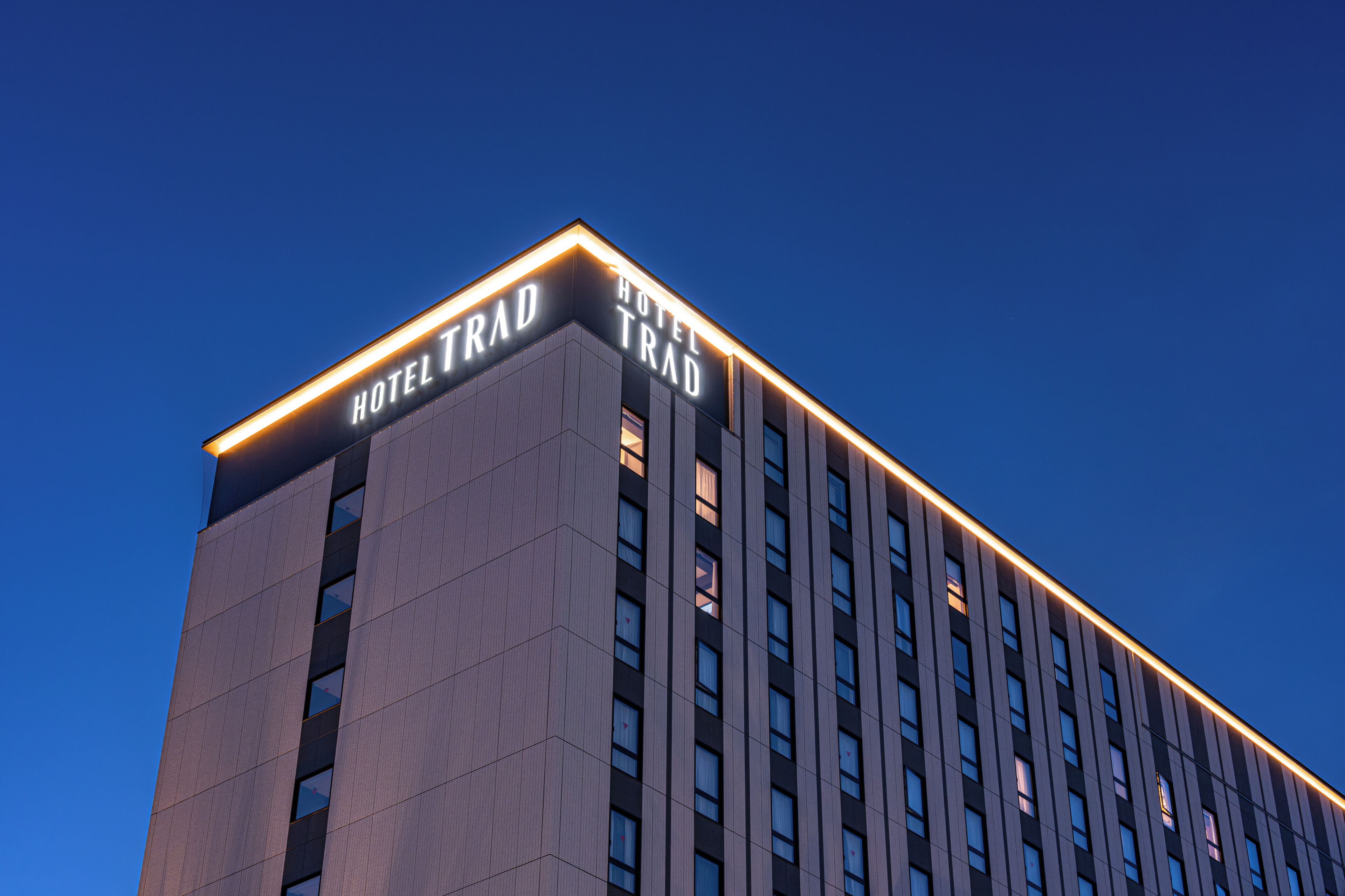Un edificio moderno di un hotel con un cartello ben visibile che riporta 'HOTEL TRAD' in alto.