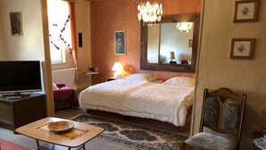 Habitación de hotel con cama, televisión, lámpara, silla y mesa.