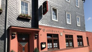 Un edificio con fachada roja y un cartel que dice 'Gasthof Meurestein'.