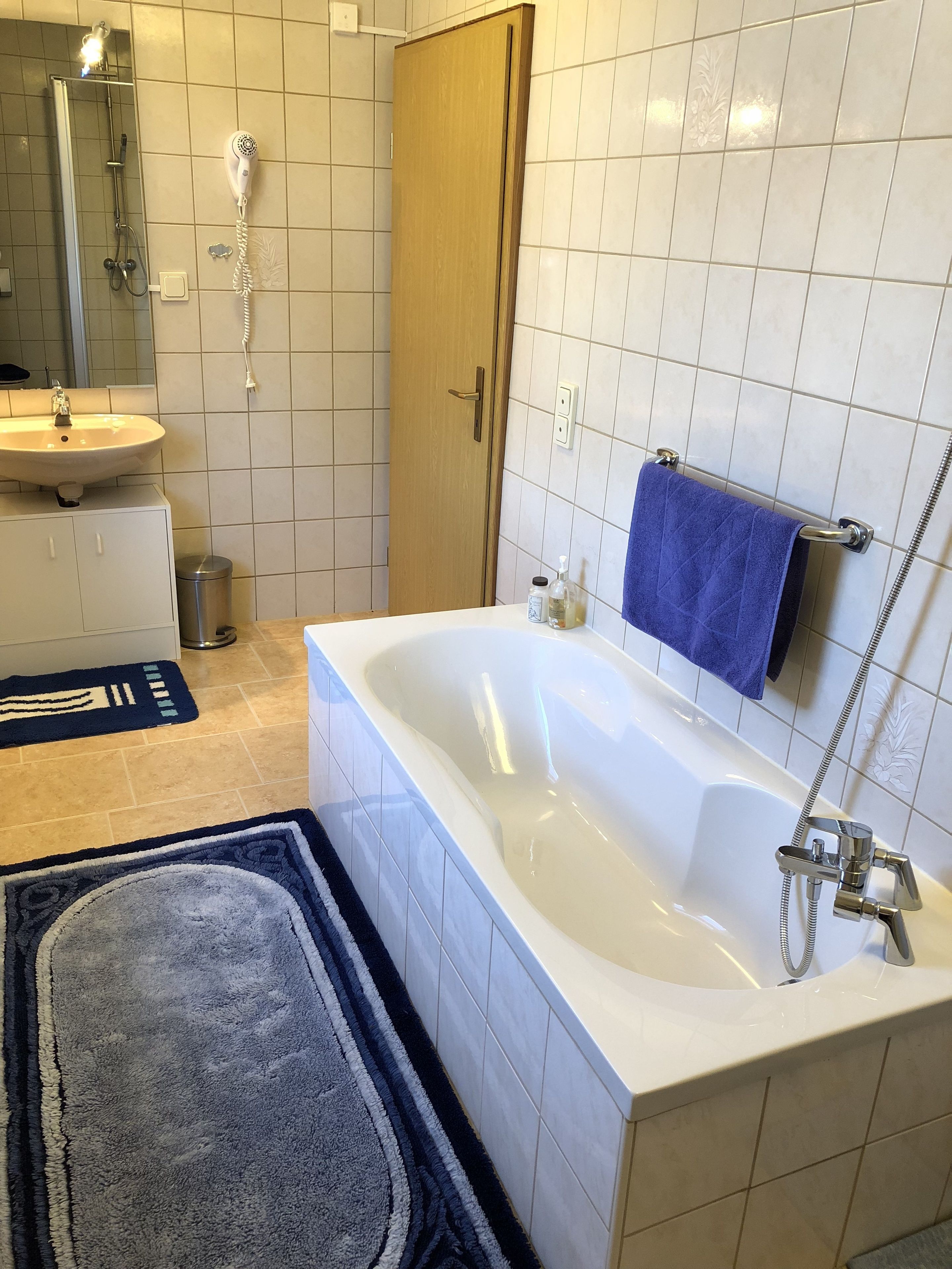 Een moderne badkamer met een bad, een wastafel, een spiegel en een douche.