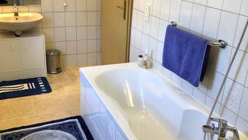 Een moderne badkamer met een bad, een wastafel, een spiegel en een douche.