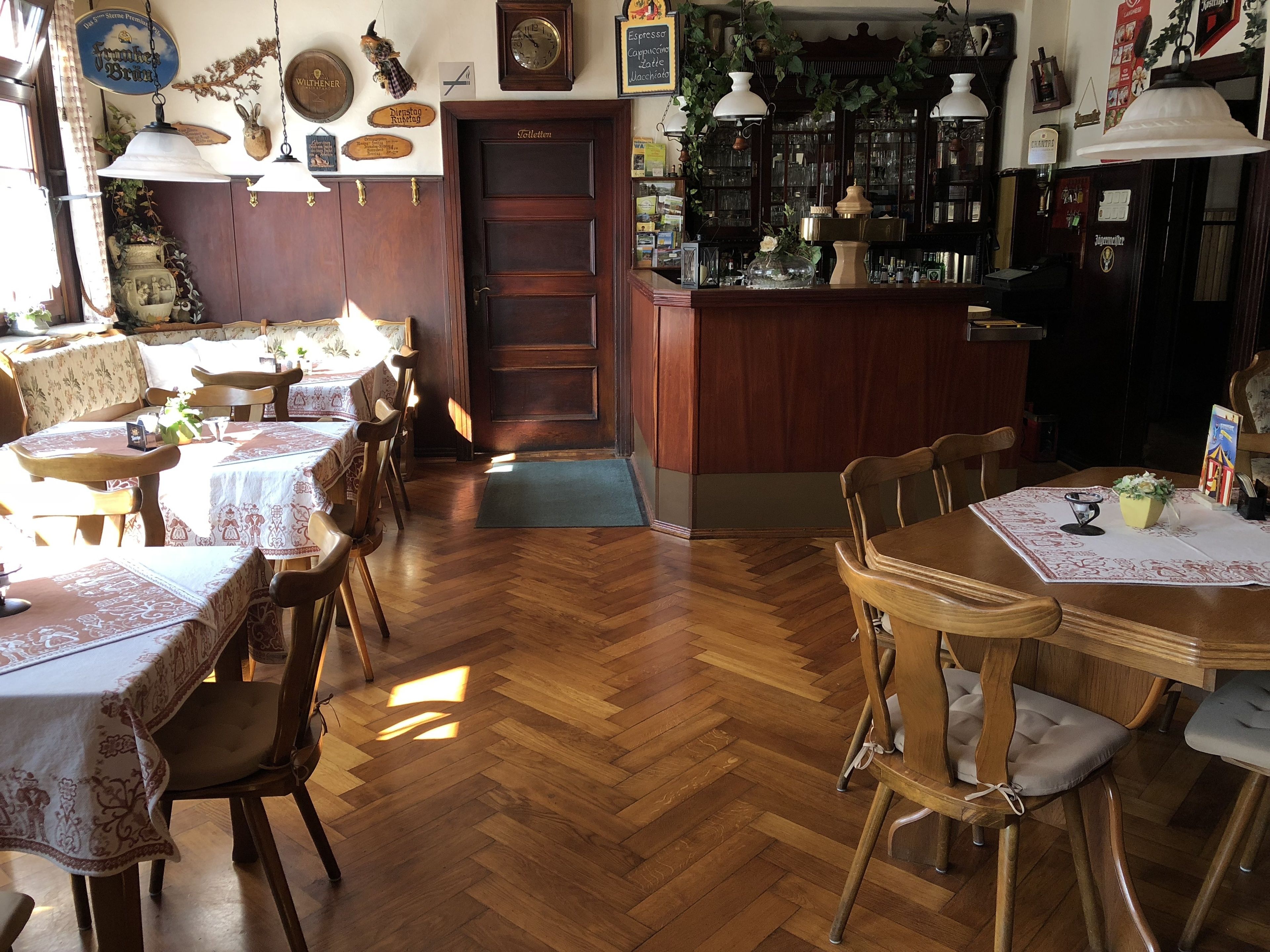 Un restaurante acogedor con muebles de madera, una zona de bar y diversas decoraciones en las paredes.