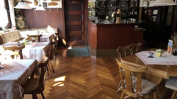 Un restaurante acogedor con muebles de madera, una zona de bar y diversas decoraciones en las paredes.