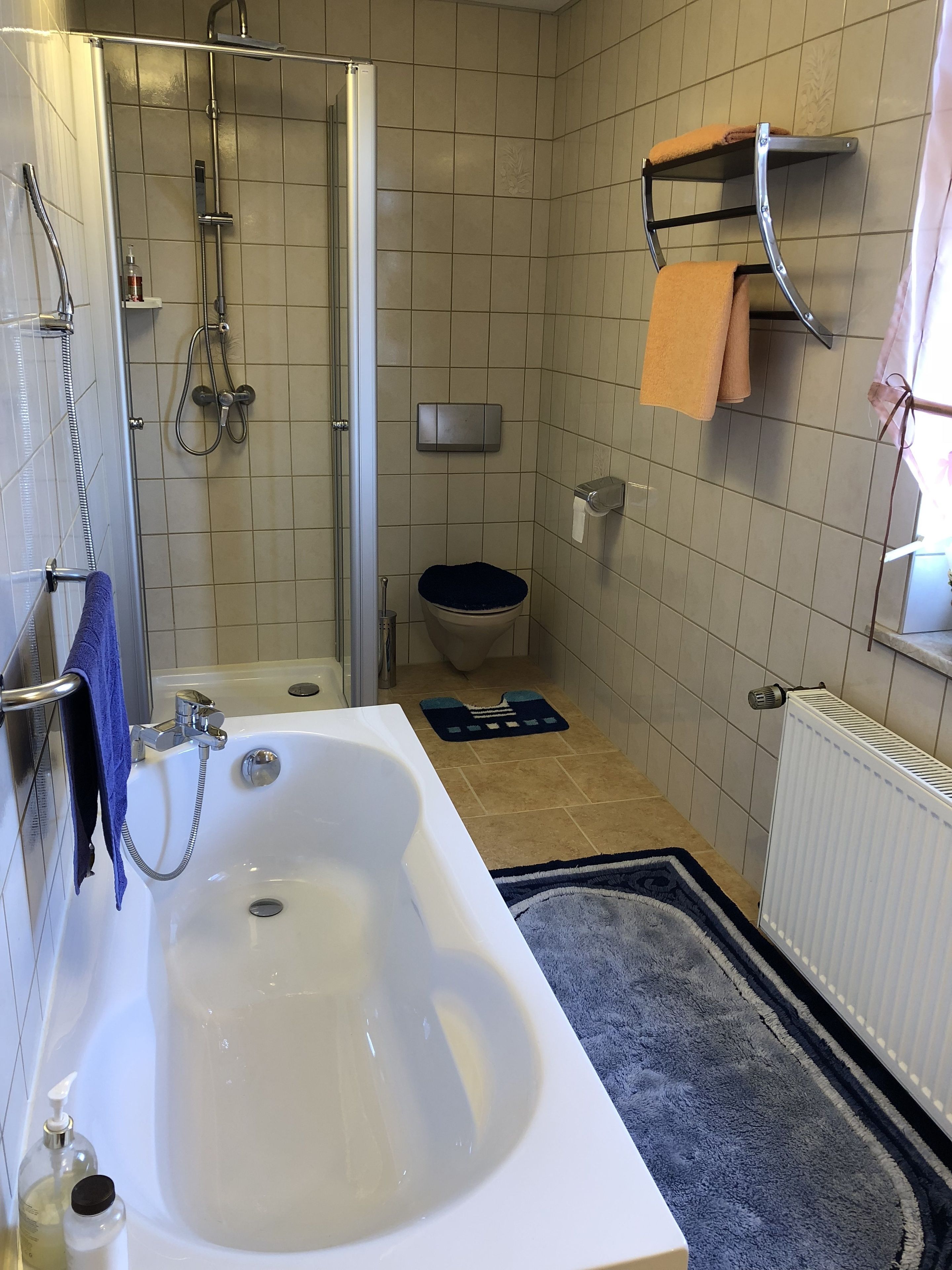 A bathroom with a bathtub, shower, toilet, and a towel rack.