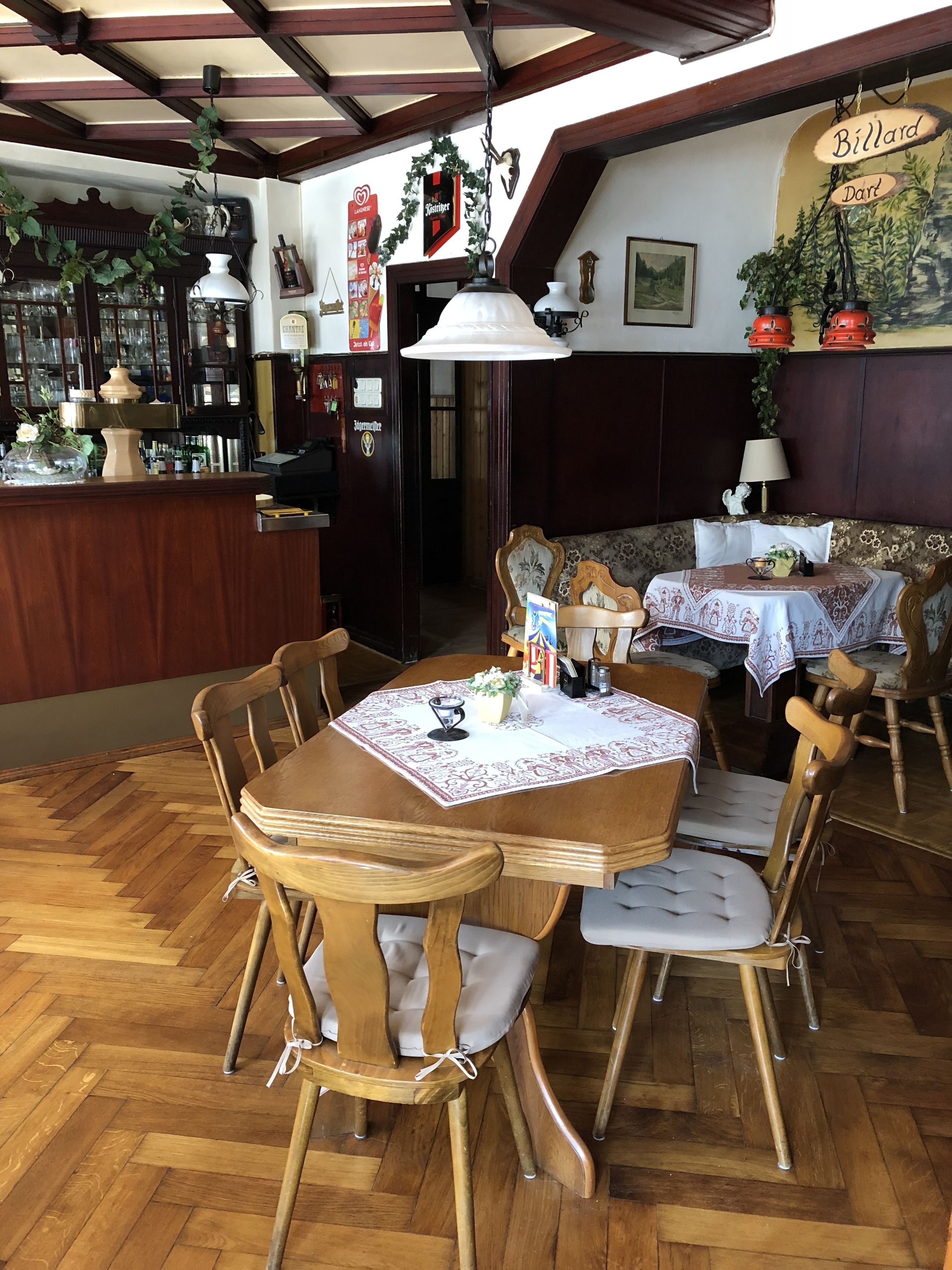 A cozy restaurant with wooden furniture, a bar area, and a billiard table.