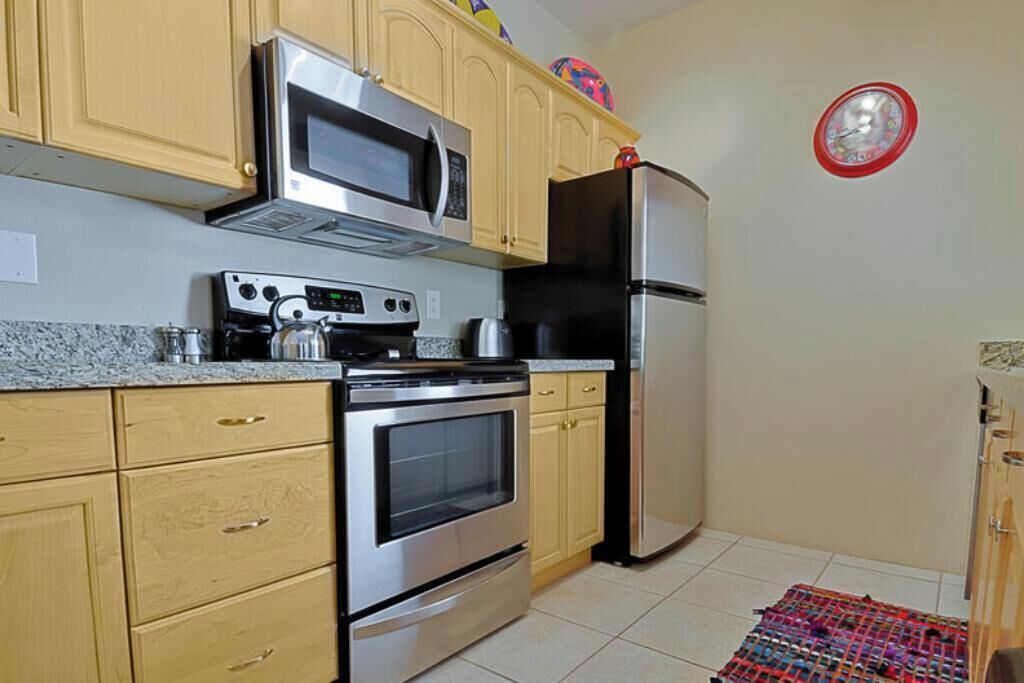 A kitchen with a microwave, oven, refrigerator, and wooden cabinets.