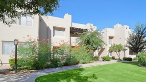 Un edificio residencial con un césped cuidado, un sendero y una farola.