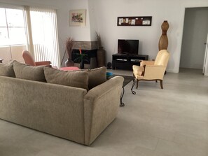 A living room with a sofa, armchairs, a TV, and a fireplace.