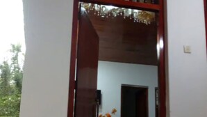 A wooden door with a glass panel, leading to a room with a white wall and a green mat on the floor. - cocos villa hikkaduwa (Hikkaduwa)