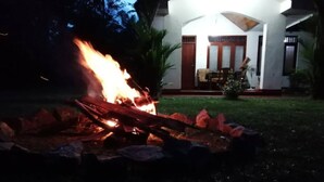 A fire burning in a garden area with a building in the background. - cocos villa hikkaduwa (Hikkaduwa)