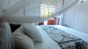 A room with a bed under a mosquito net, white walls, and a window with curtains. - cocos villa hikkaduwa (Hikkaduwa)