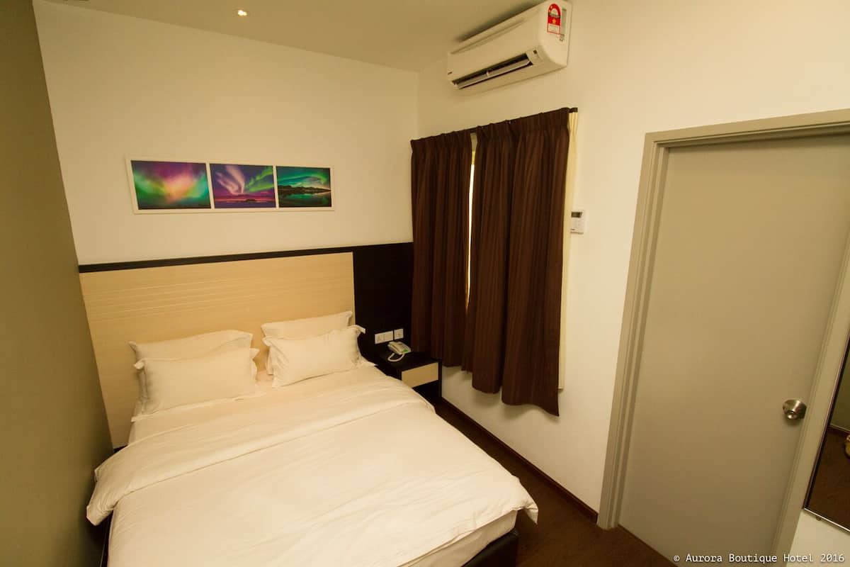 A hotel room with a bed, a nightstand, a phone, and a door.