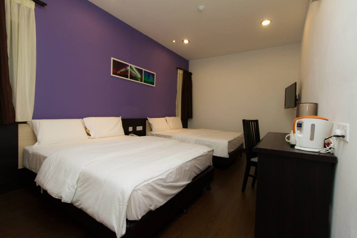 A hotel room with two beds, a desk, and a coffee maker.