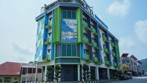 Un hotel de varias plantas con diseño moderno, con balcones y un letrero llamativo.