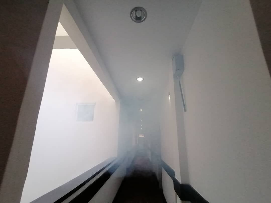 Ein schmaler, schwach beleuchteter Gang mit einem schwarz-weiß gestreiften Boden, einer weißen Wand und einer Deckenleuchte.