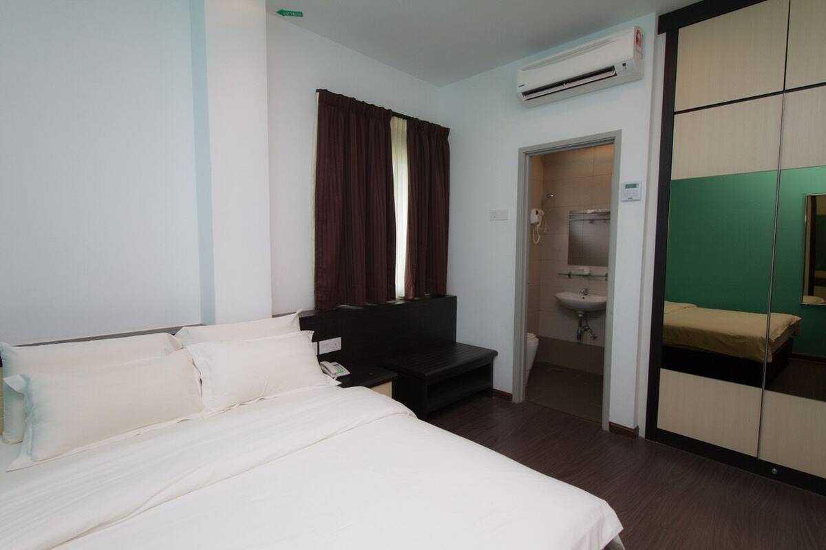 A hotel room with a bed, a desk, a wardrobe, and a bathroom.