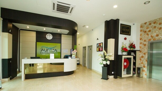 Zona de recepción de un hotel con un mostrador curvo, un reloj y un certificado enmarcado en la pared.