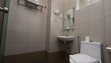 A bathroom with a toilet, sink, towel rack, and a mirror.