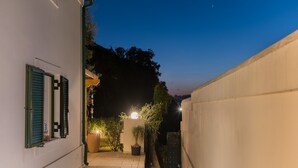 Une ruelle étroite, avec un bâtiment blanc sur la gauche, une porte verte et un mur sur la droite.
