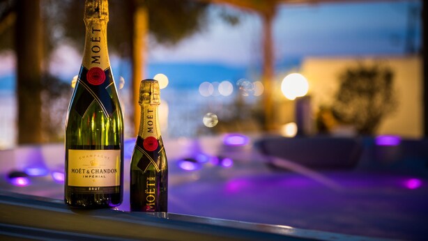 Deux bouteilles de champagne Moët & Chandon sur un comptoir de bar, avec un arrière-plan flou de lumières et une vue sur la ville.